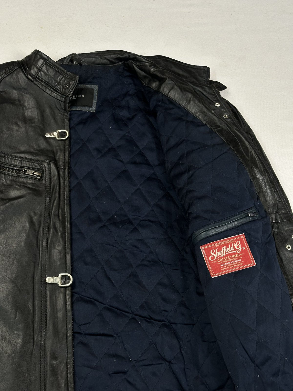 Detail of the inner zip pocket and red woven label set into the navy quilted lining