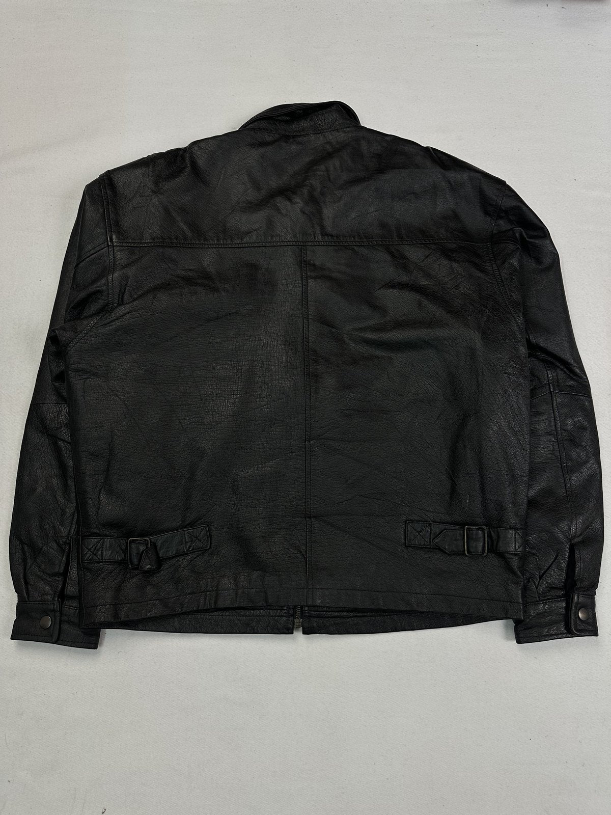 Back of the XL black jacket laid flat showing the two adjustable straps at the waist