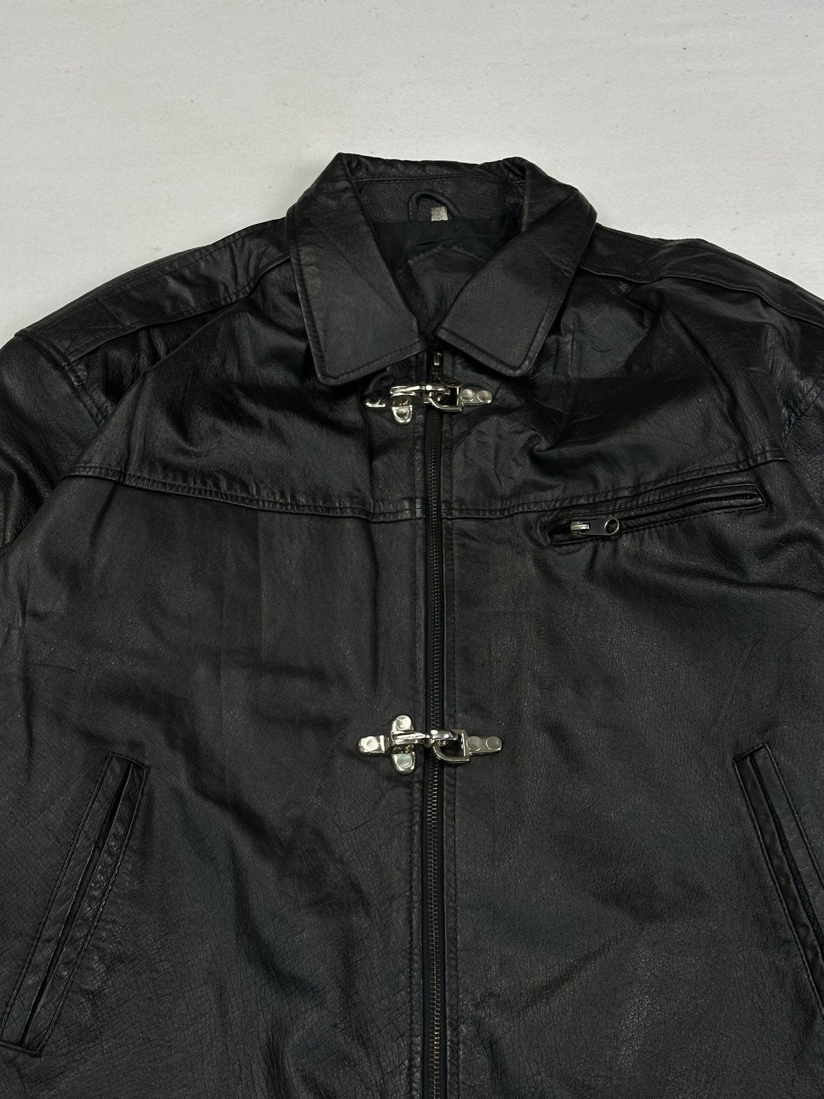 Close view of the pointed shirt collar and the metal clasps down the front of the jacket