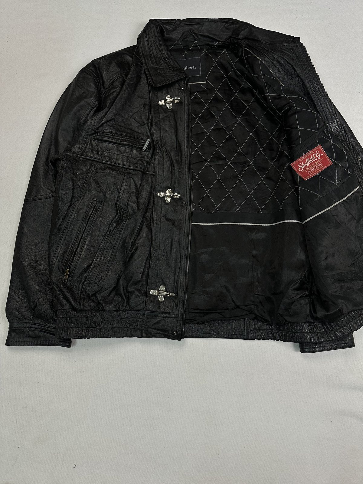 Jacket laid open to show the quilted black lining and the clasps along the front edge