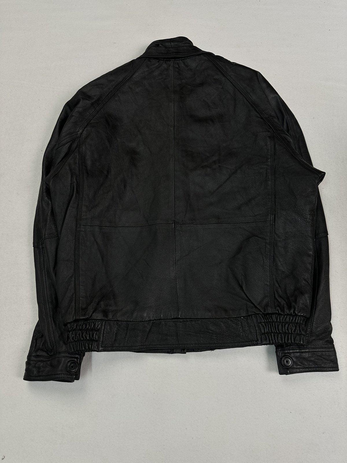 Back of the size L black bomber laid flat, showing the seamed panel and elasticated waist