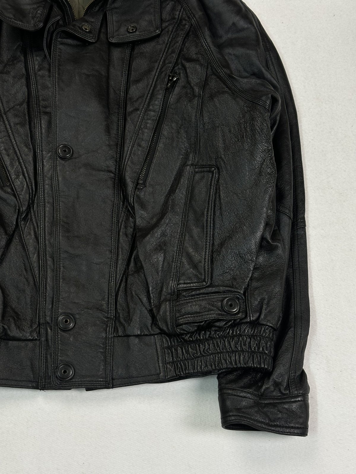 Angled view of the right pocket flap and gathered waist on the black leather bomber