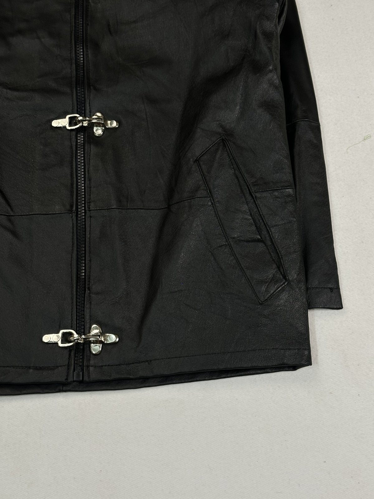 Angled view of the right slash pocket and the clasps set against the black leather