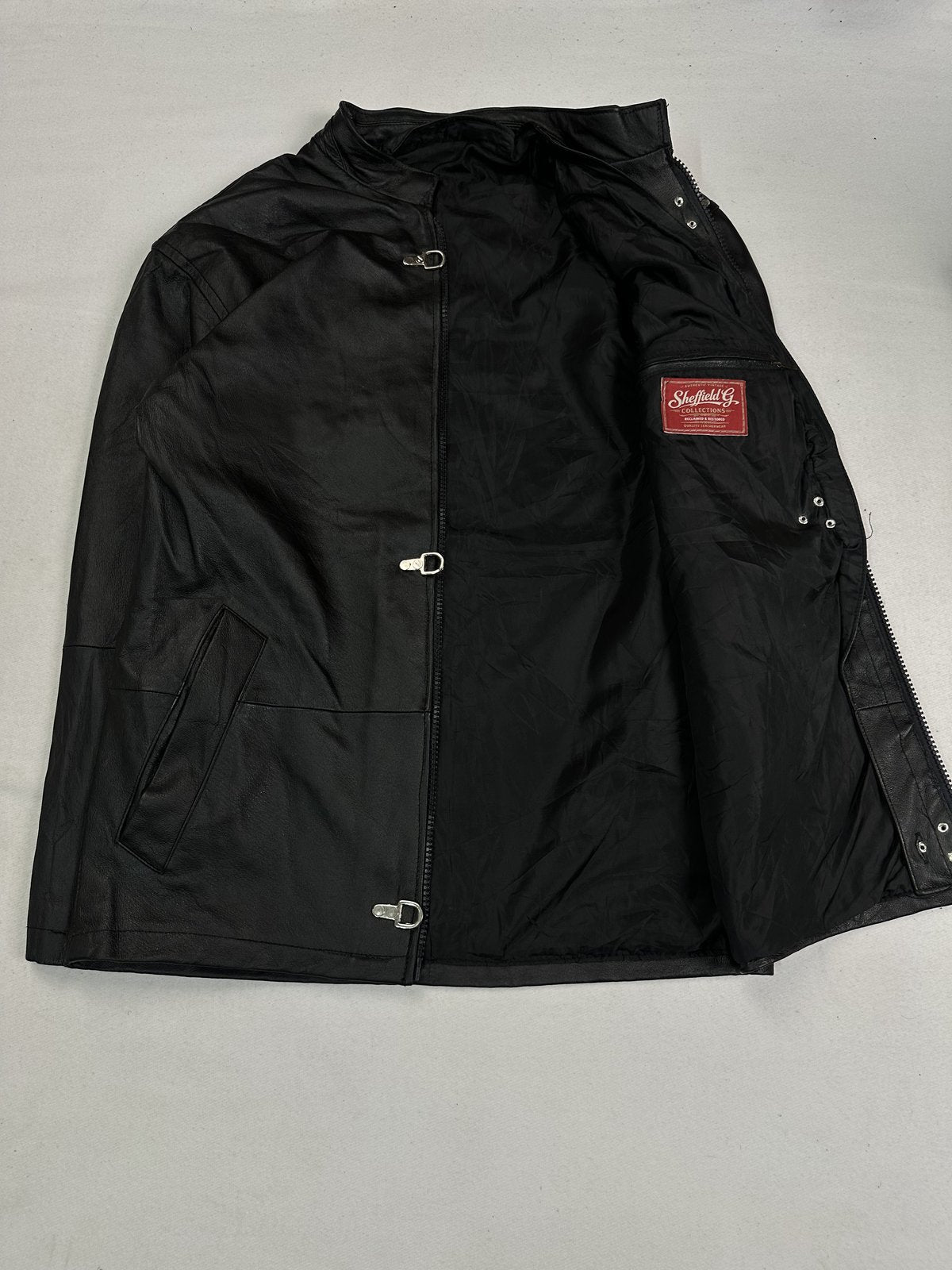 Black lining of the long cut jacket, held open to show the interior and clasps