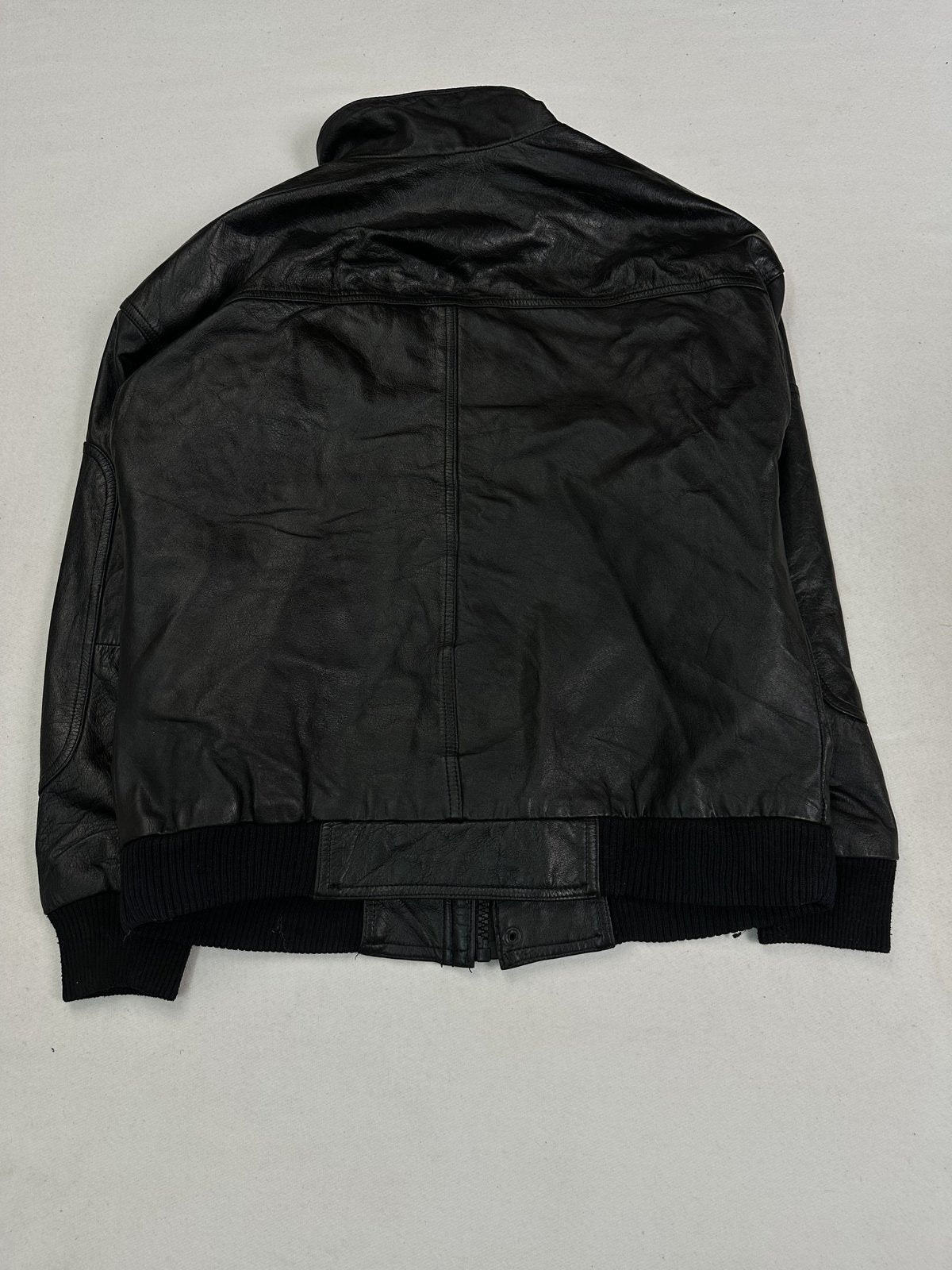 Ribbed knit hem gathering the waist of the black leather bomber