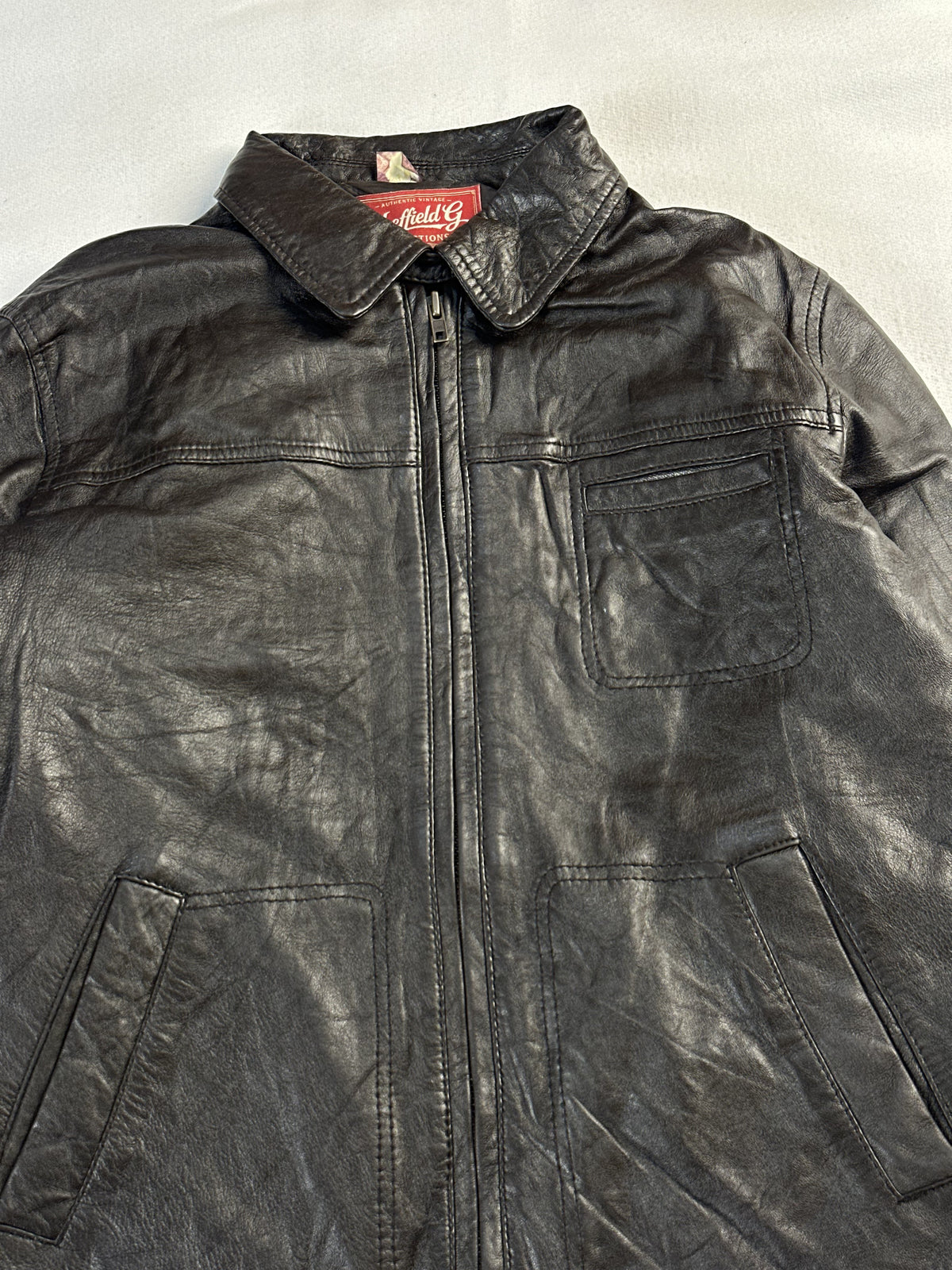 Close view of the pointed collar and neck label above the zipped front