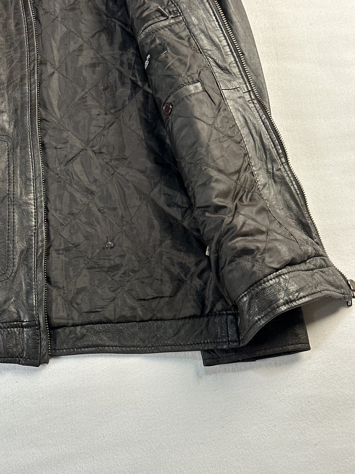 Quilted interior lining of the brown jacket held open to show the sleeve and hem