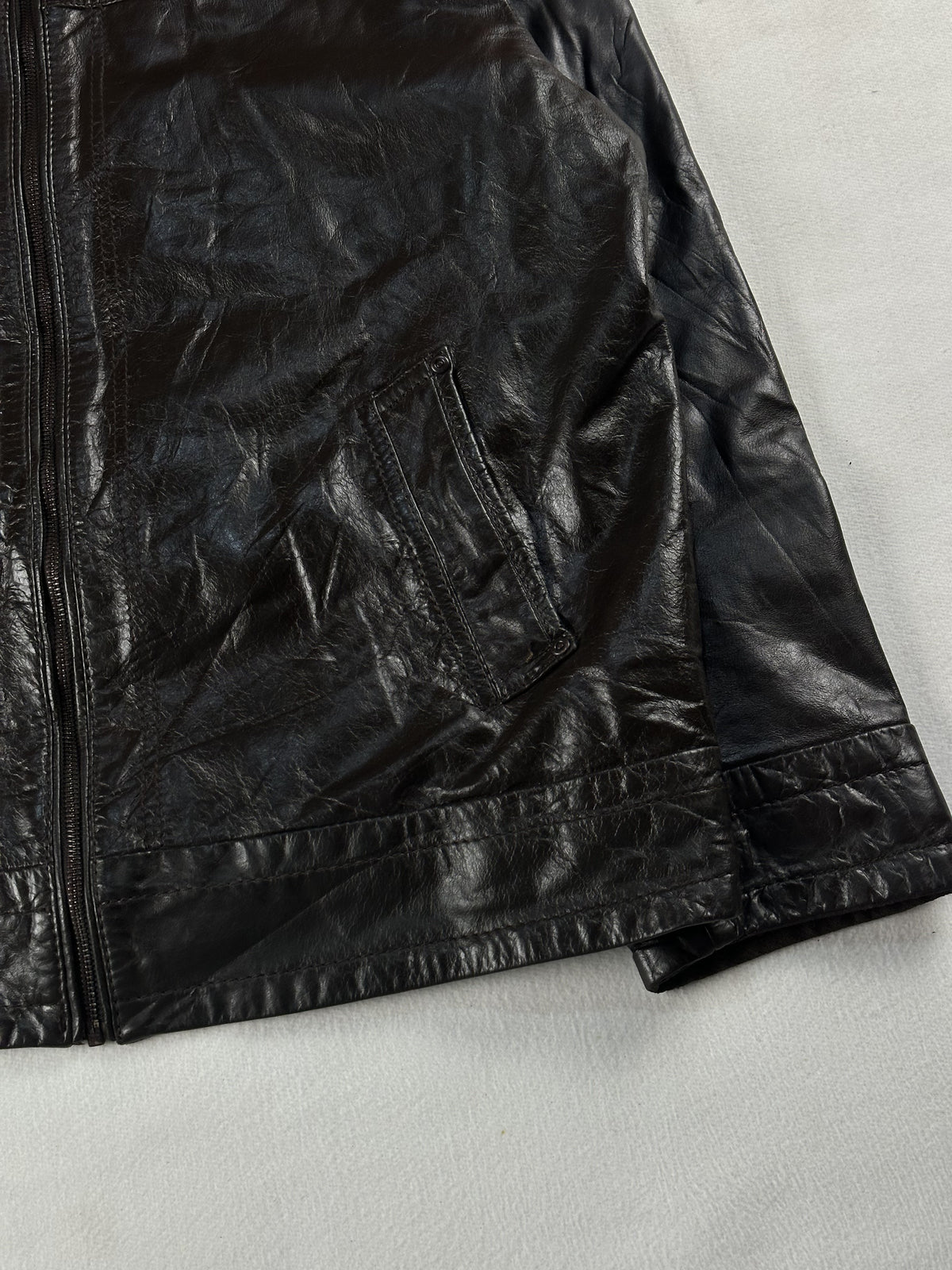 Lower right front of the brown jacket with its slash pocket and zip running to the hem