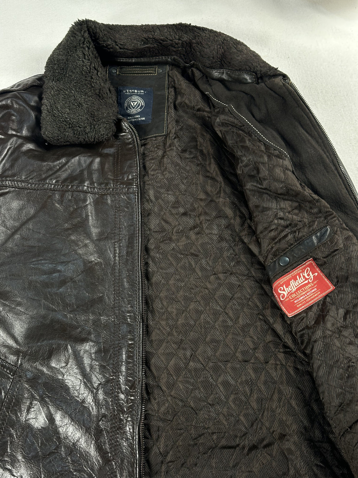 Quilted lining and red inner label inside the brown leather cafe racer, held open