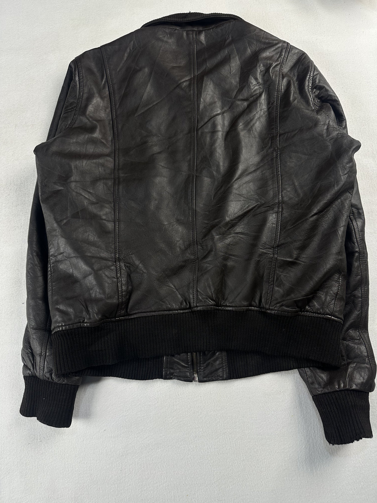 Back of the size L brown flight jacket laid flat, showing the deep knitted rib hem
