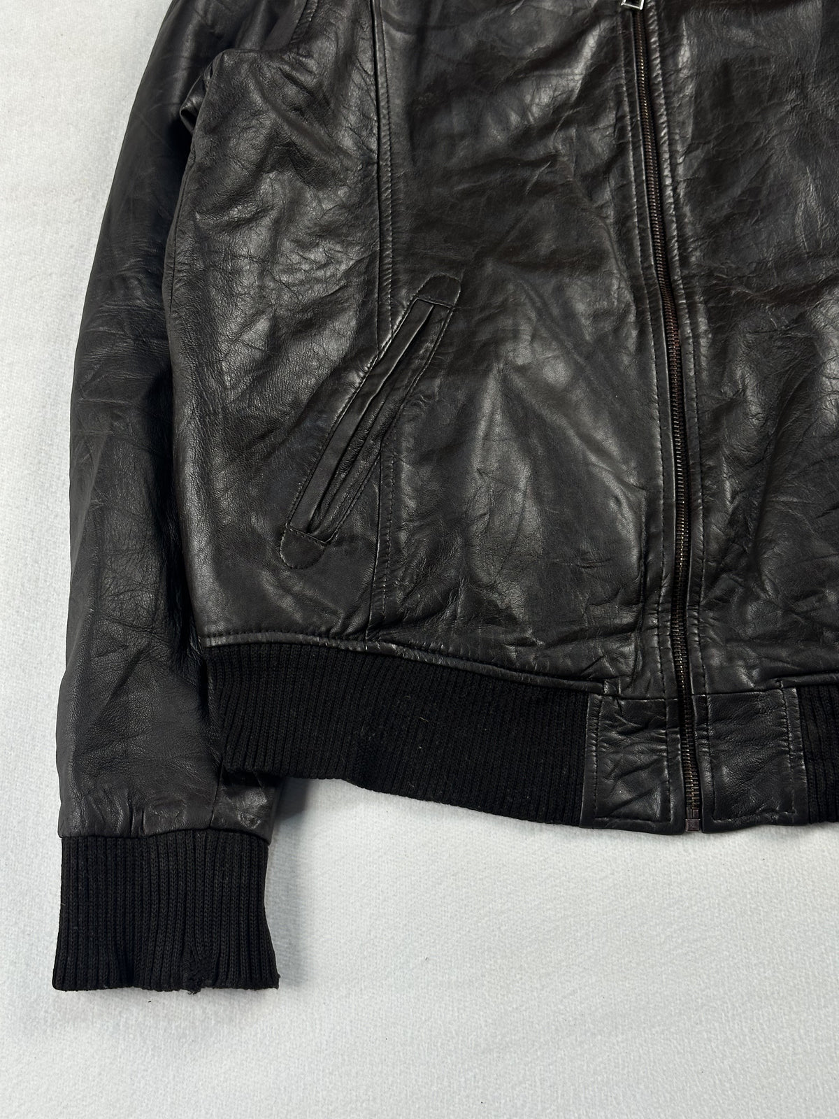 Angled zip pocket on the left front sitting just above the ribbed hem and cuff