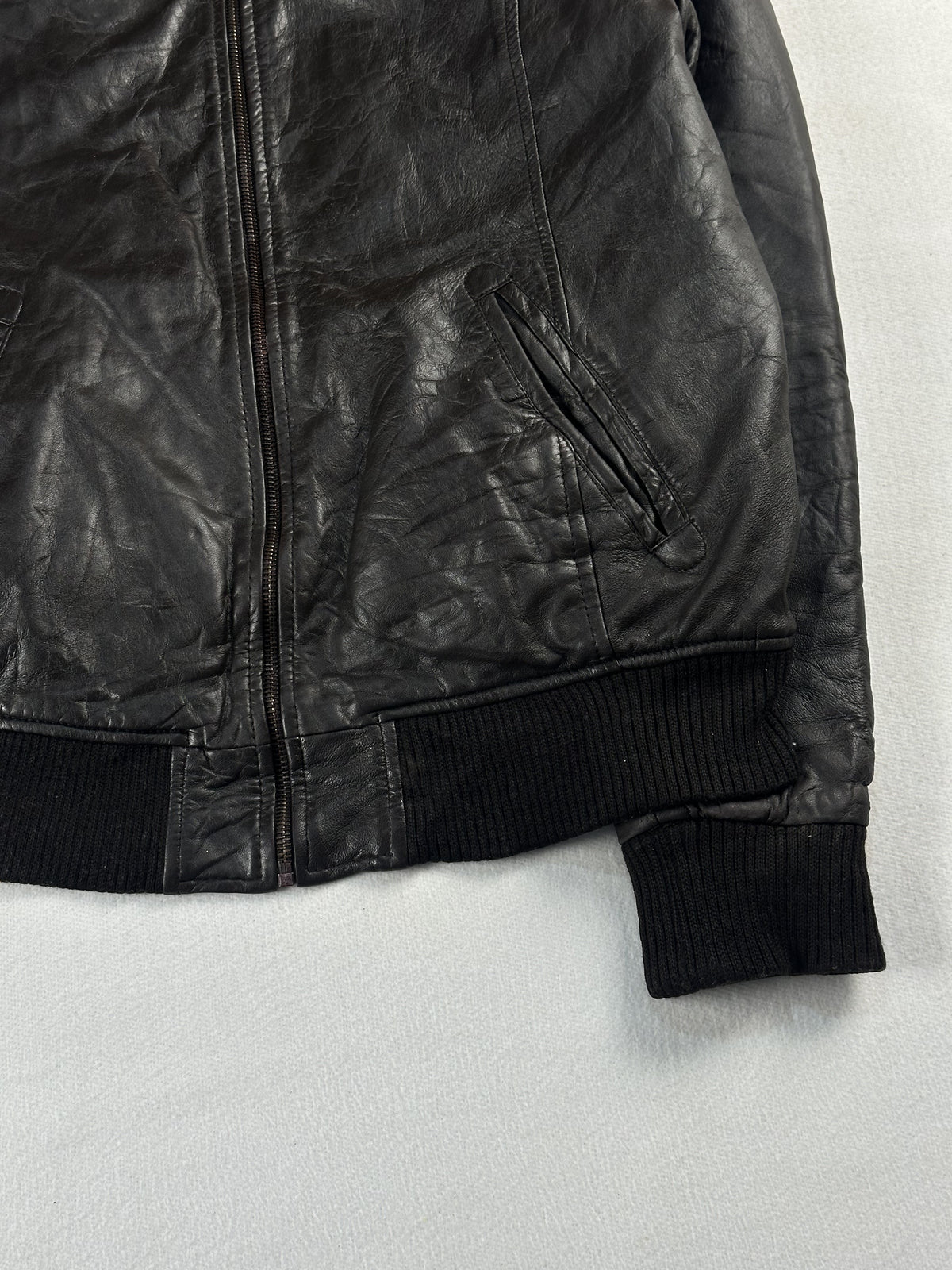 Welt pocket at the right hip with the rib hem and cuff of the brown leather jacket