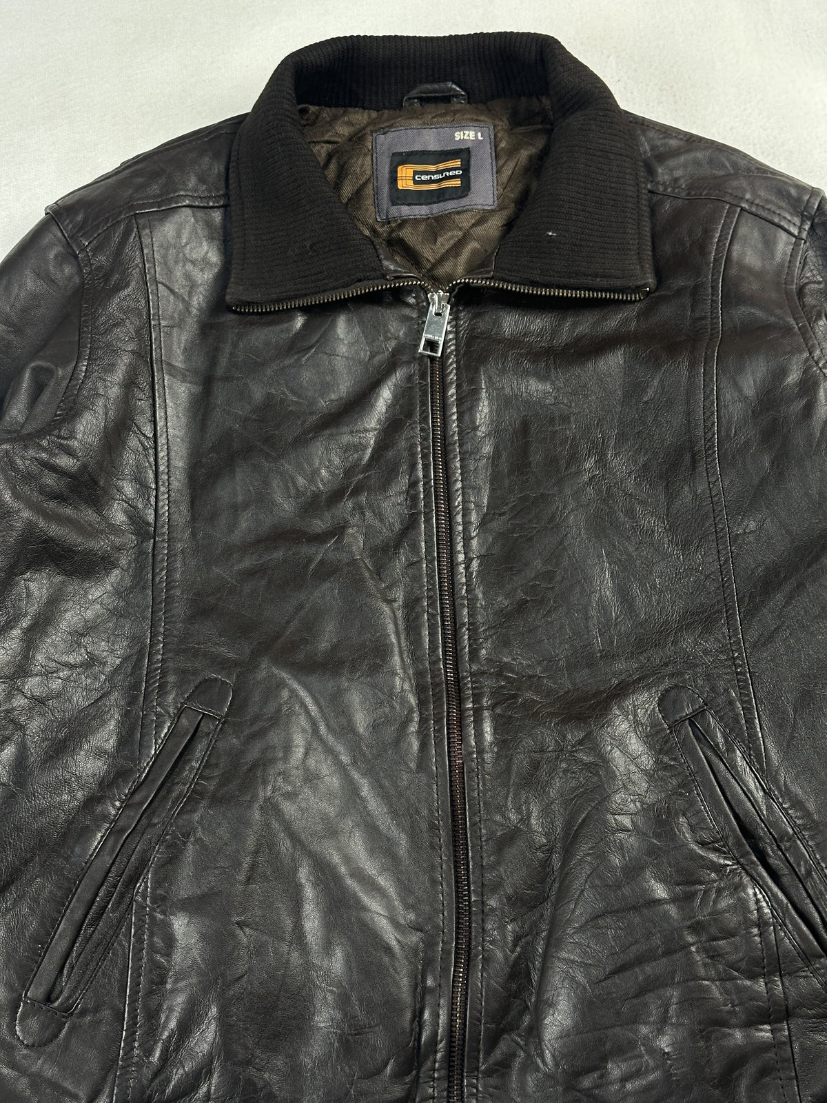 Close view of the ribbed knit collar, neck label and chunky zip pull at the neck