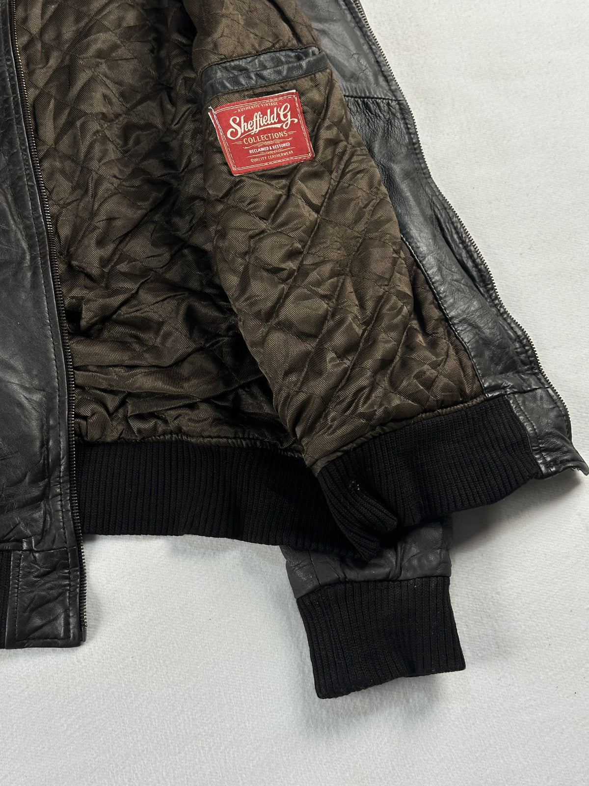 Quilted olive lining and interior label inside the brown jacket, held open