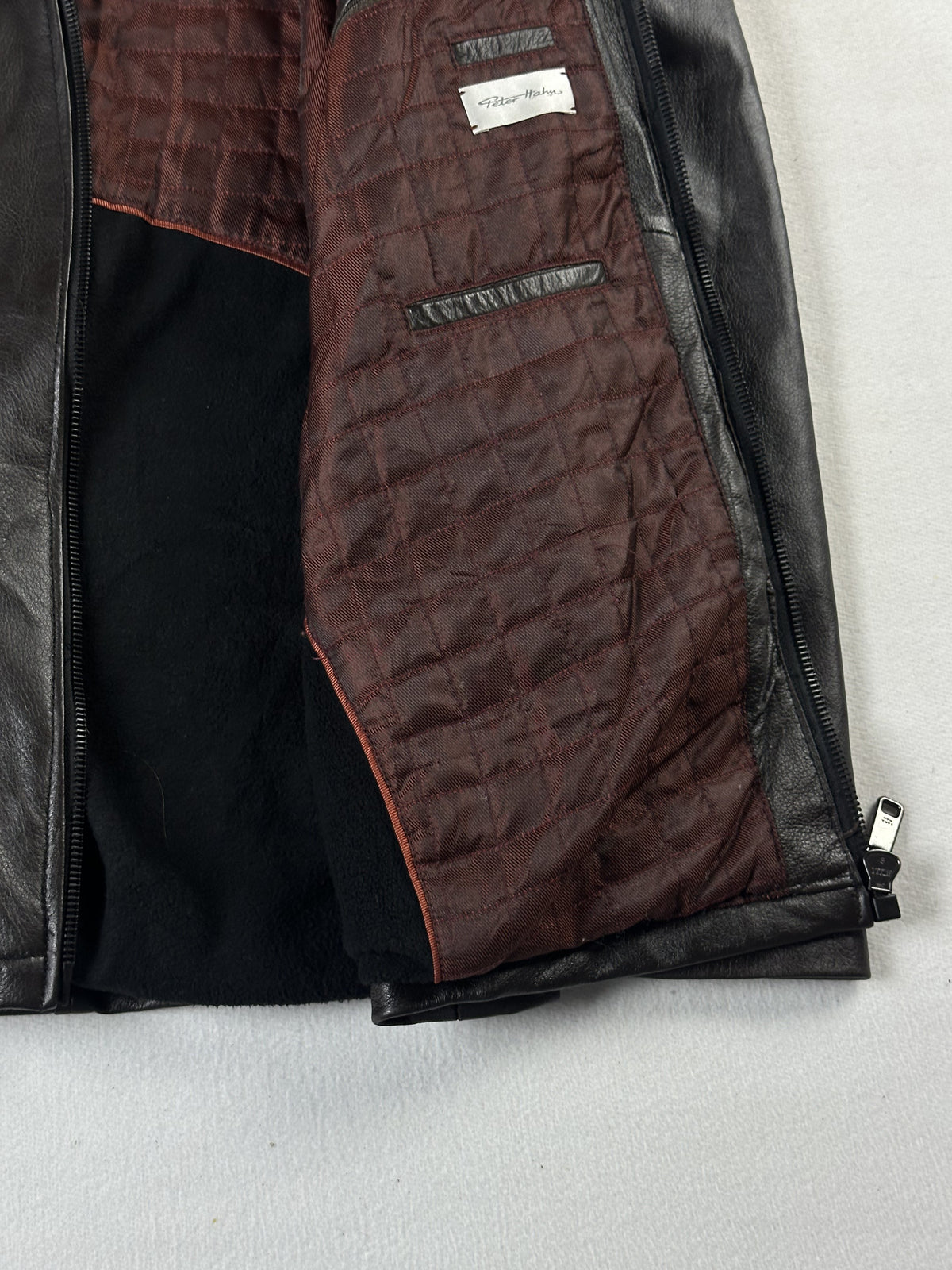 Burgundy quilted lining held open inside the jacket, with zipped inner pockets