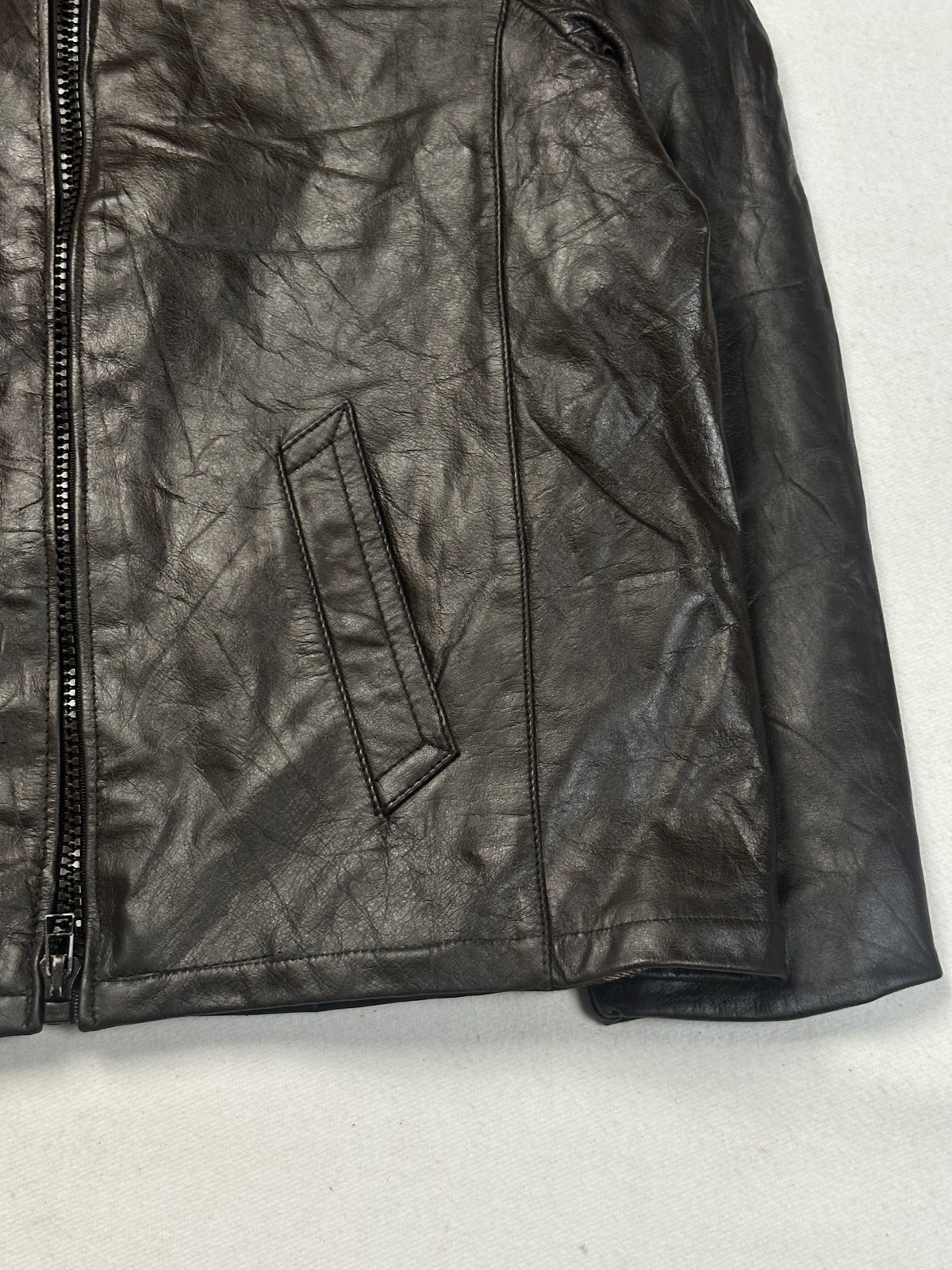 Lower right front of the brown jacket with its welt pocket beside the front zip