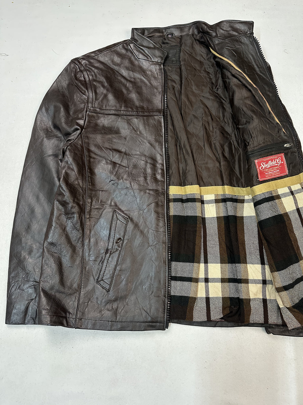 Cream and yellow tartan check lining revealed inside the open brown jacket