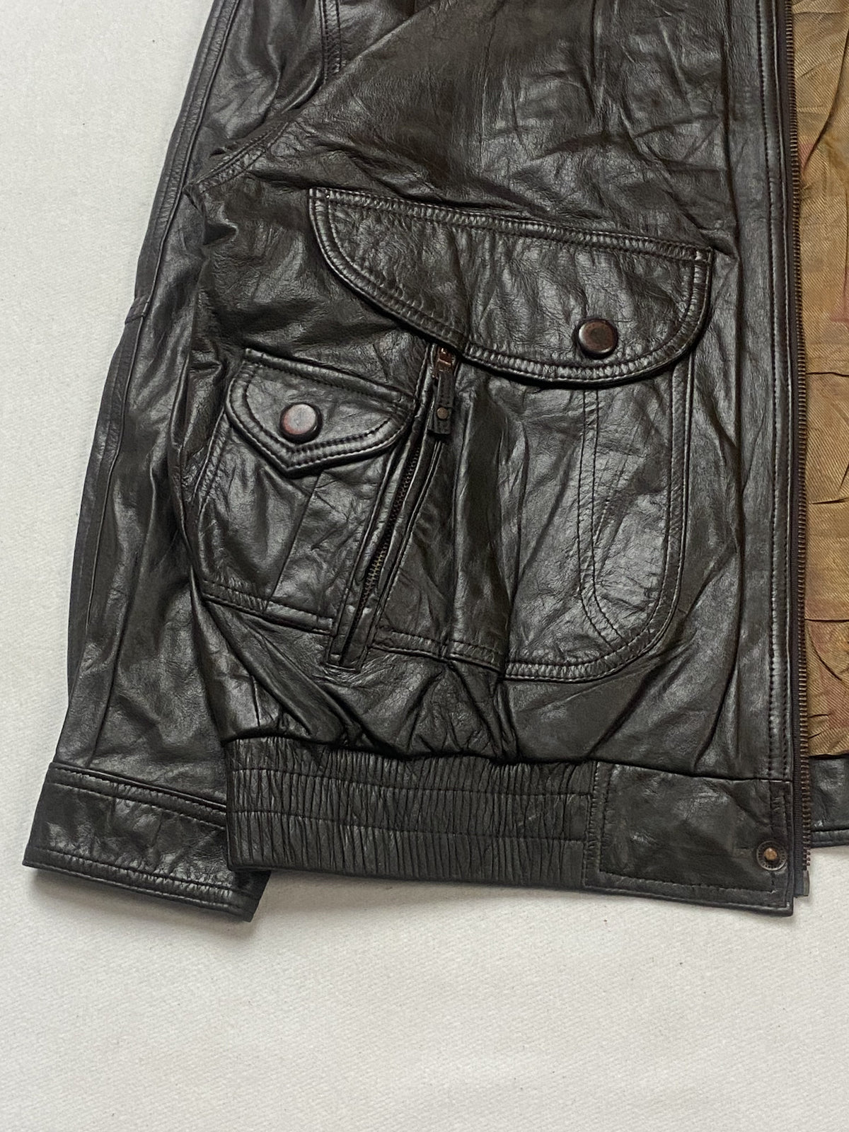 Stud-fastened bellows pocket and zip slit above the ribbed waistband