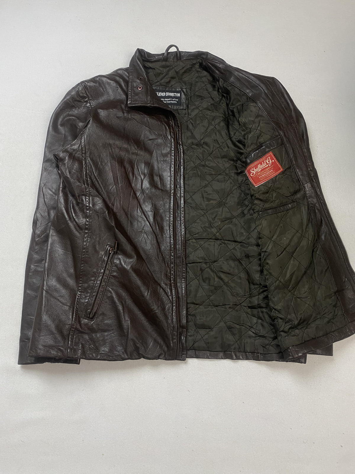 Olive green quilted lining inside the cafe racer, held open to show the interior