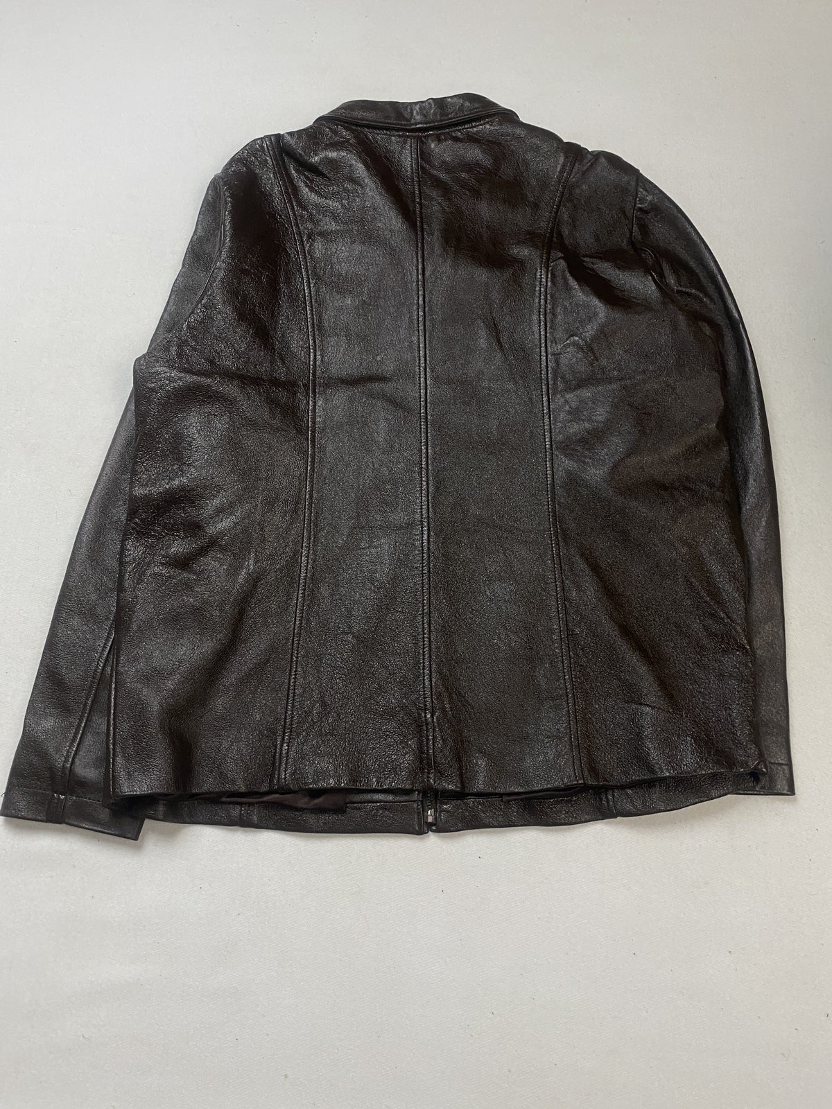 Rear view of the brown leather jacket laid flat with its seamed back panel