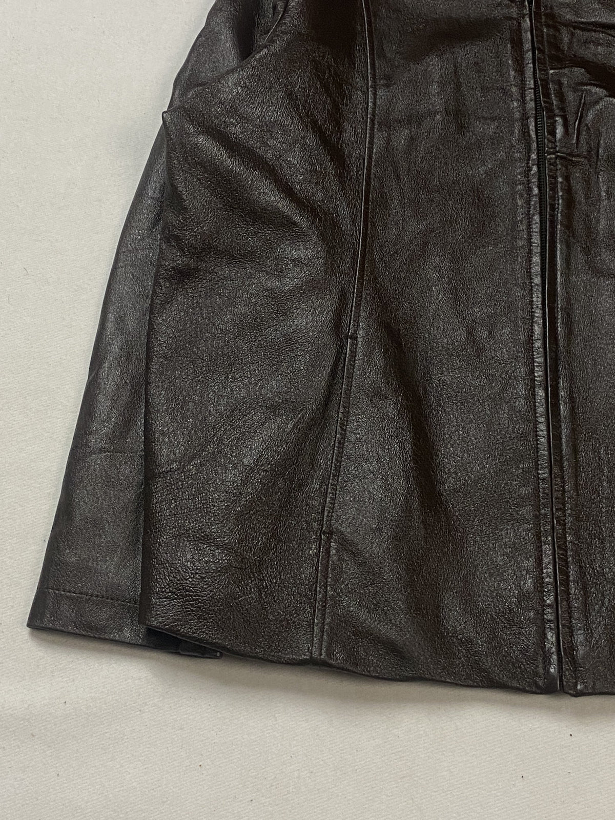 Lower left side of the brown jacket showing the vertical seam and plain hem