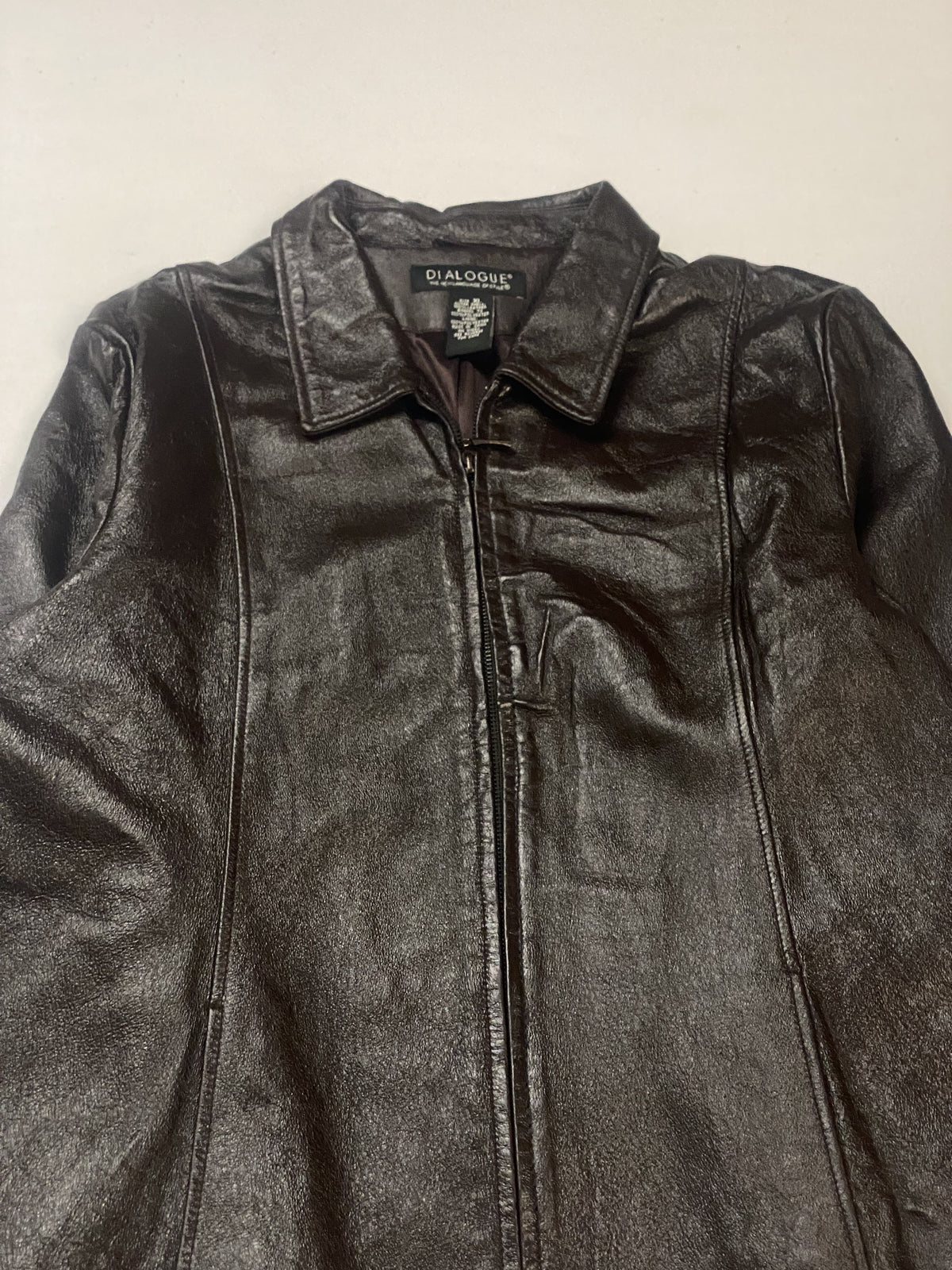 Close view of the pointed collar and neck label above the front zip