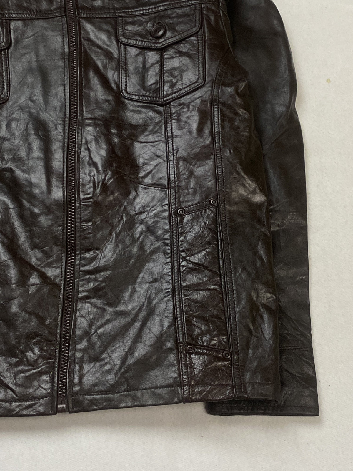 Right hem and cuff of the brown field jacket beside the open front zip