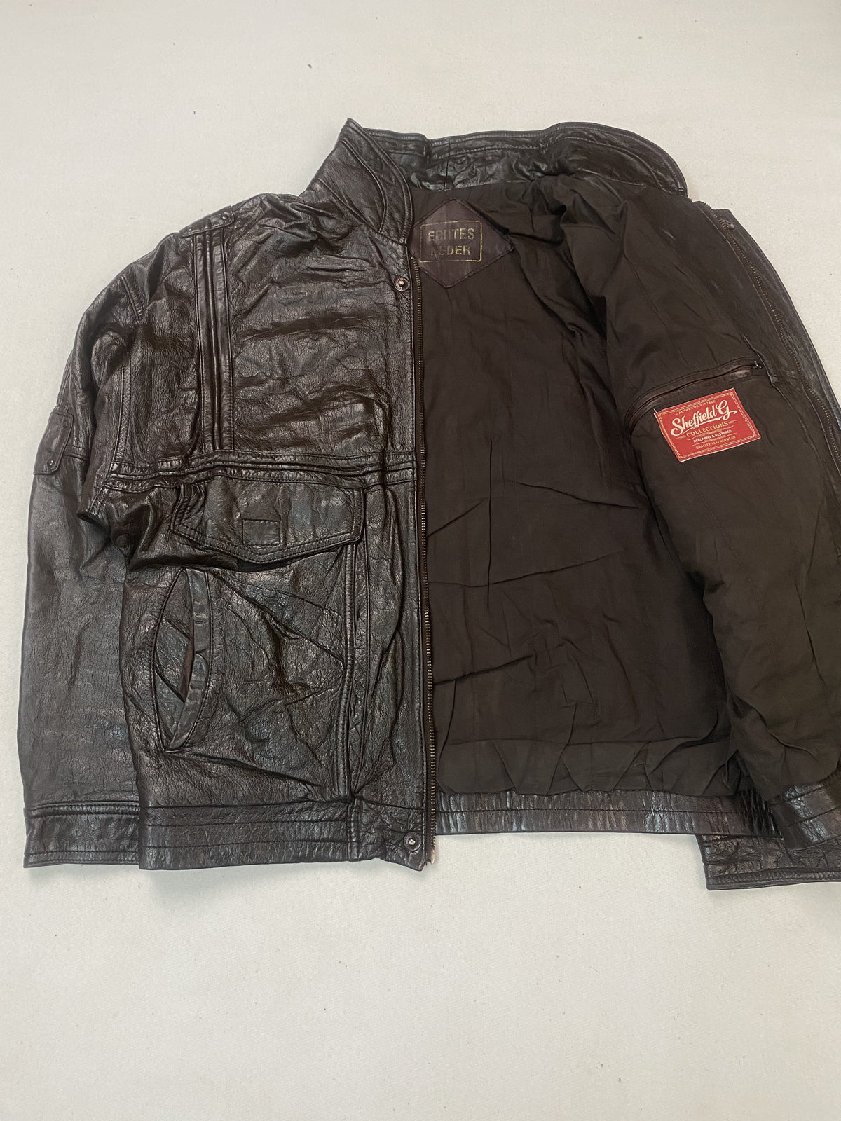 The jacket held open to show its plain brown lining and inner sleeve label