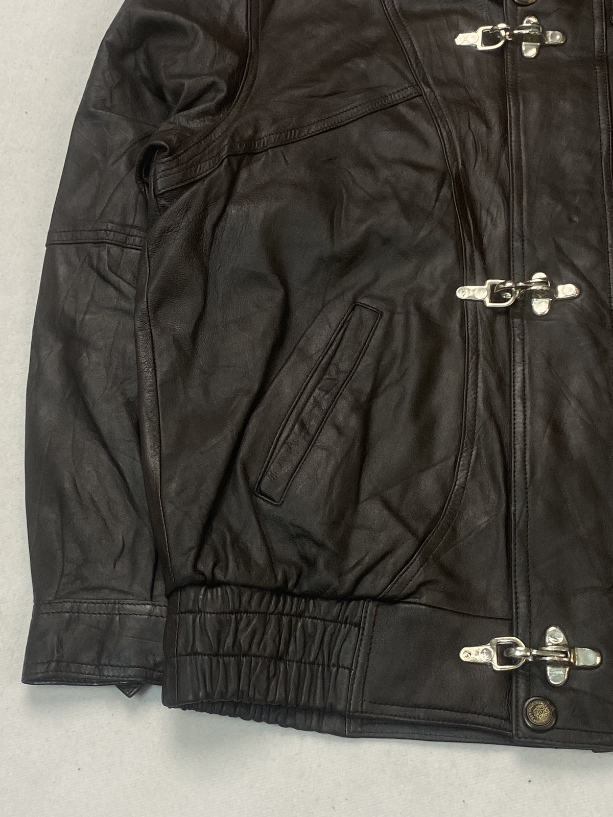 Detail of a welt hand pocket beside the silver toggle fastenings and gathered waist
