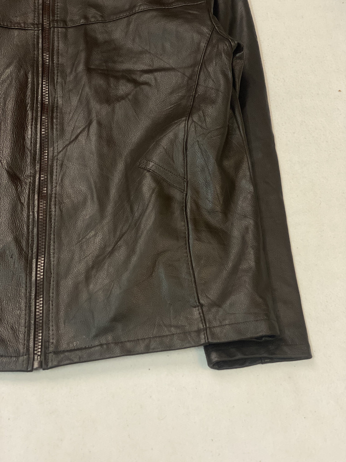Detail of a slanted welt pocket beside the front zip, with the cuff turned back
