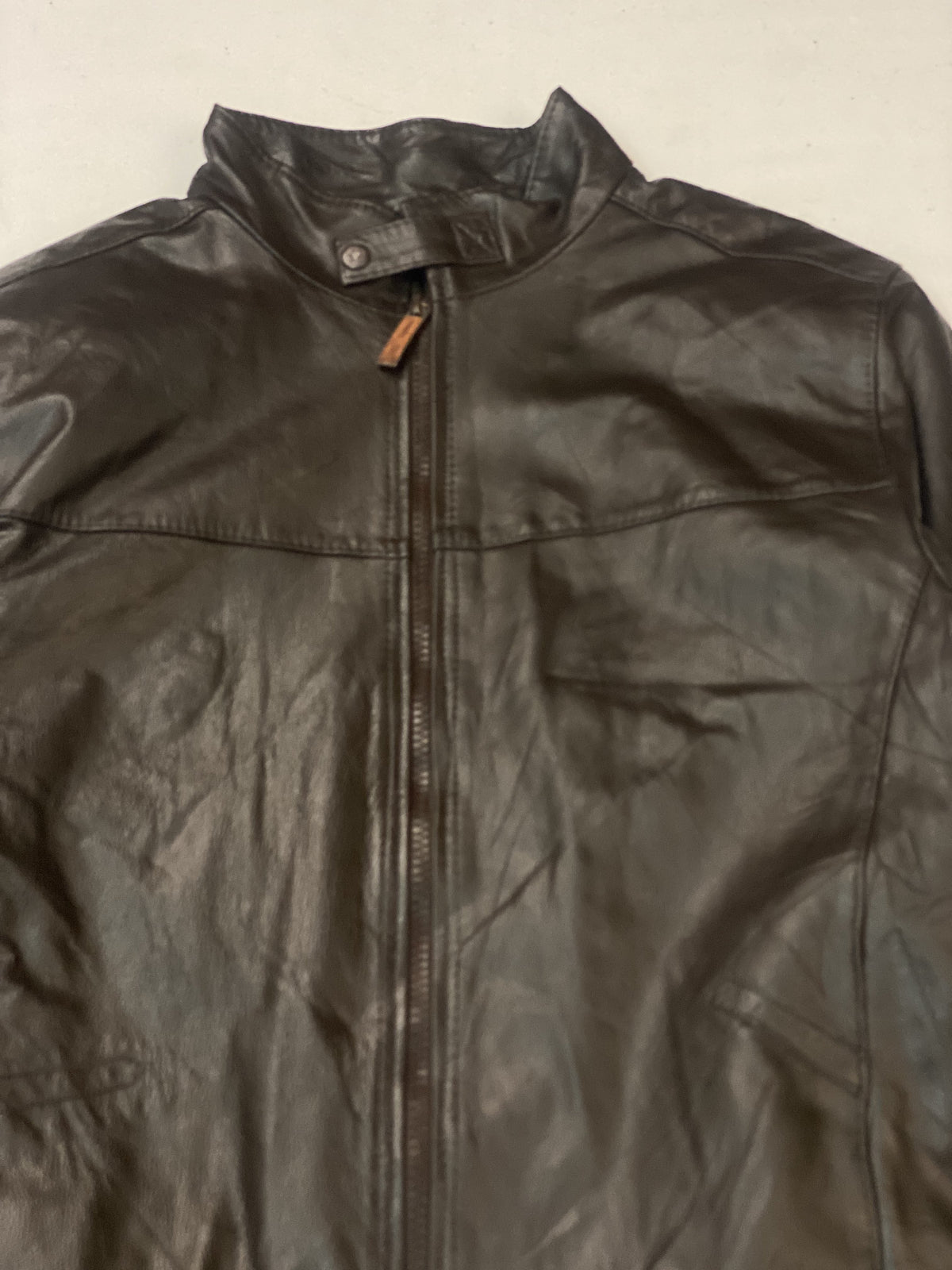 Close view of the leather pull tab at the top of the zip on the band collar
