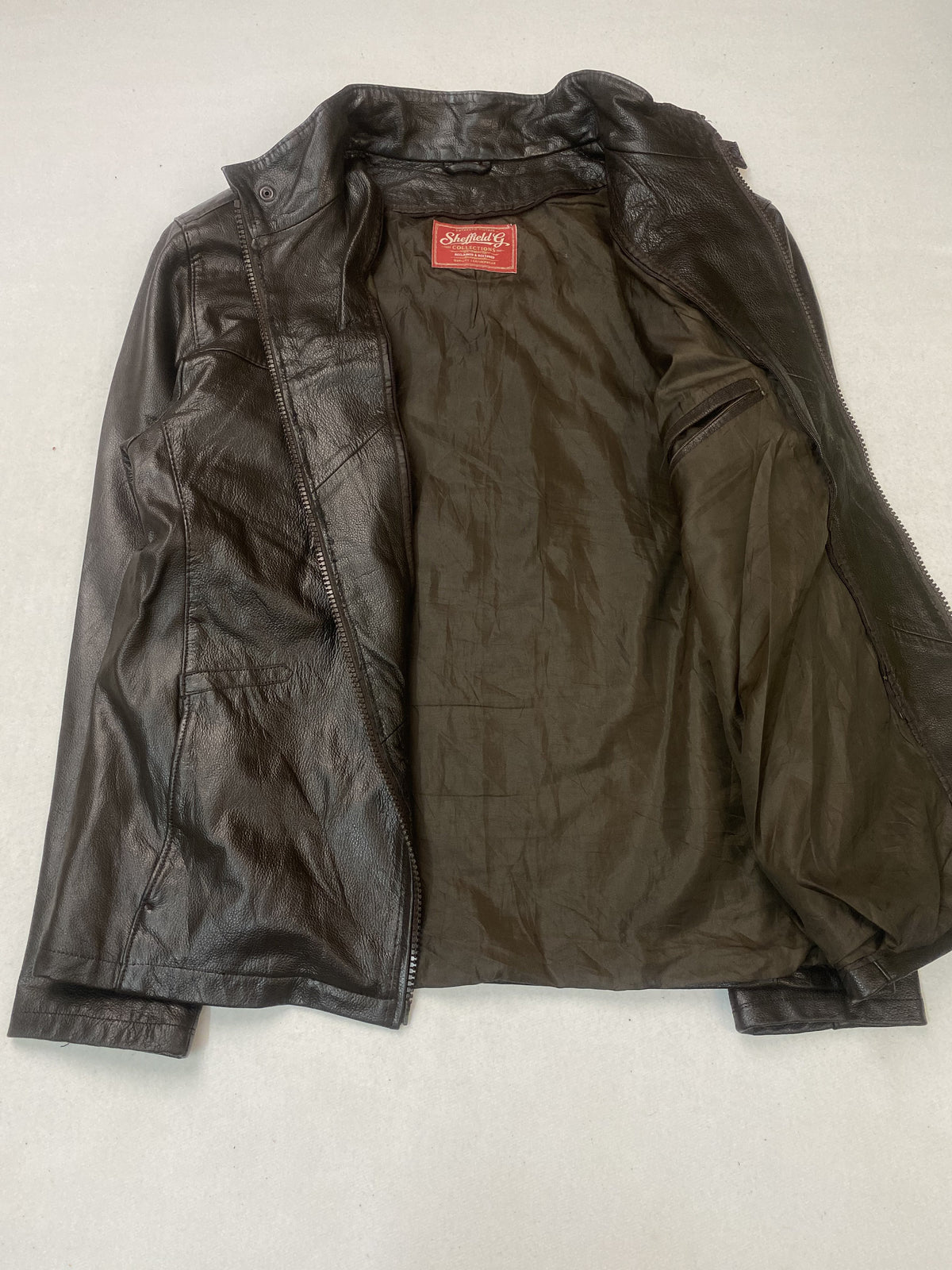 Olive lining held open inside the jacket, with the woven label at the neck