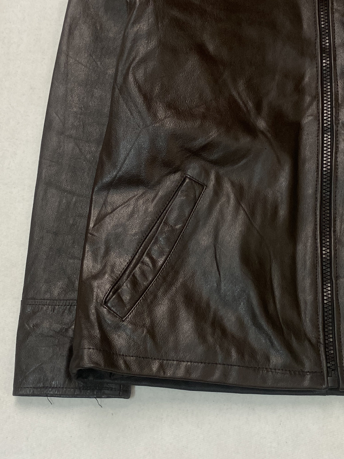Detail of a slanted welt pocket beside the front zip and the straight hem