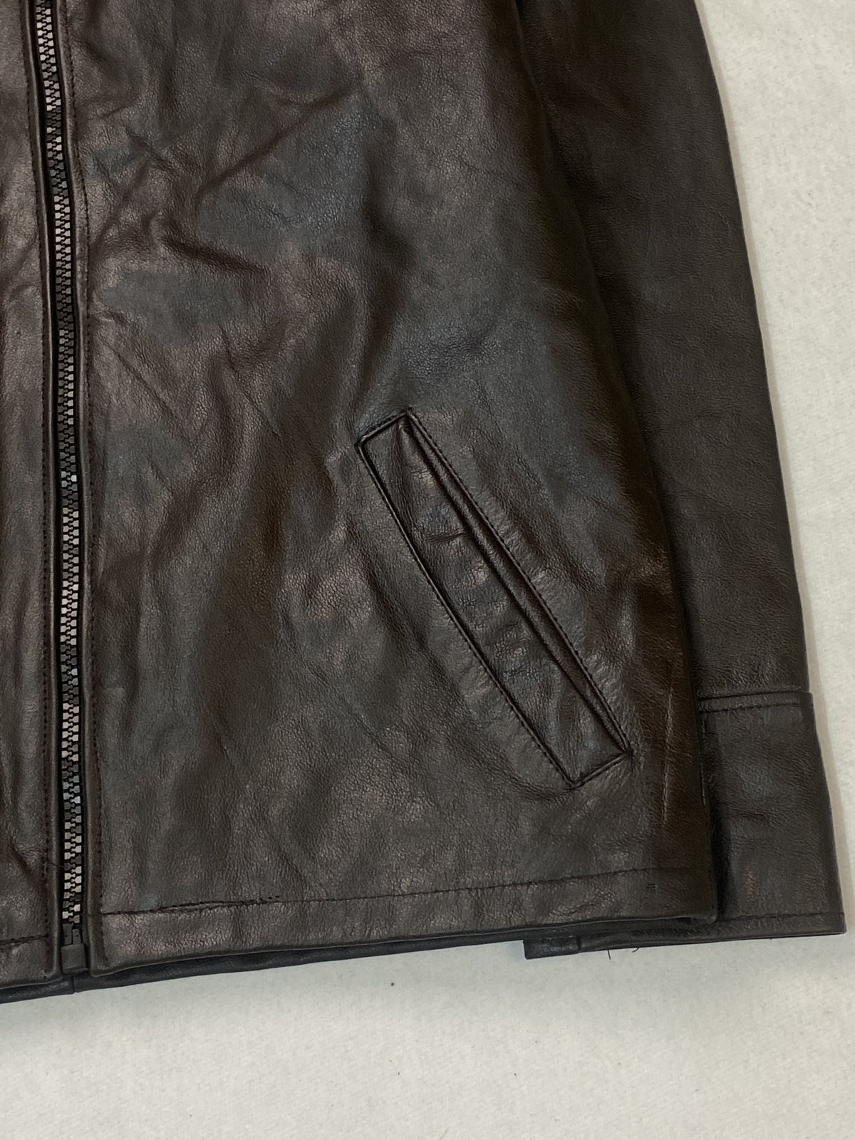 Close view of the right welt pocket, the hem edge and the plain cuff