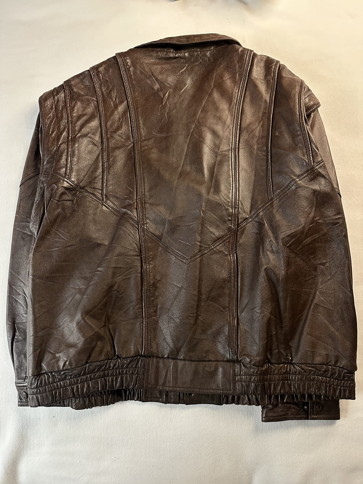 Back of the jacket laid flat with the gathered elastic hem running across the base