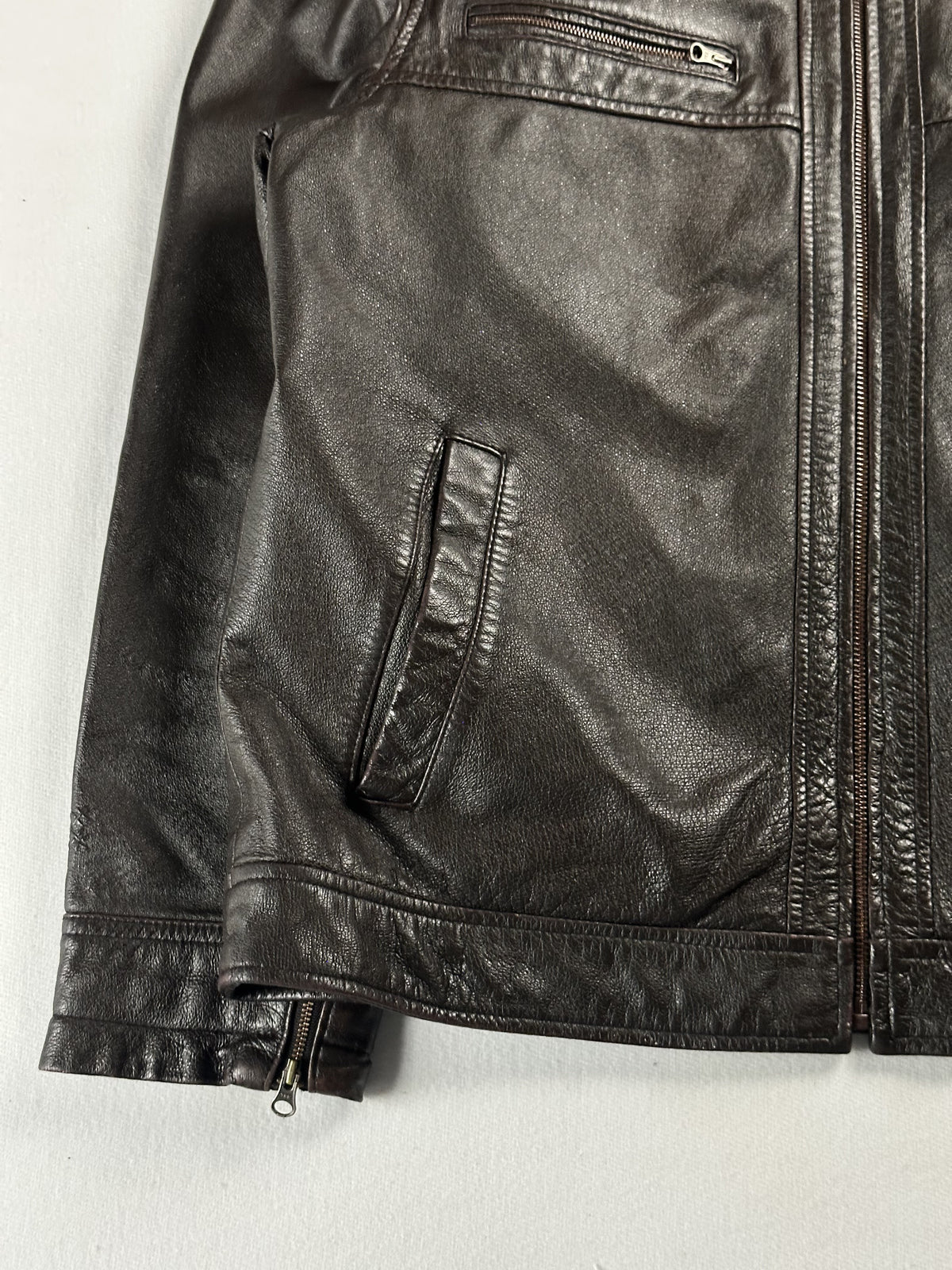 Lower front detail with a slanted welt pocket, hem band and zipped cuff