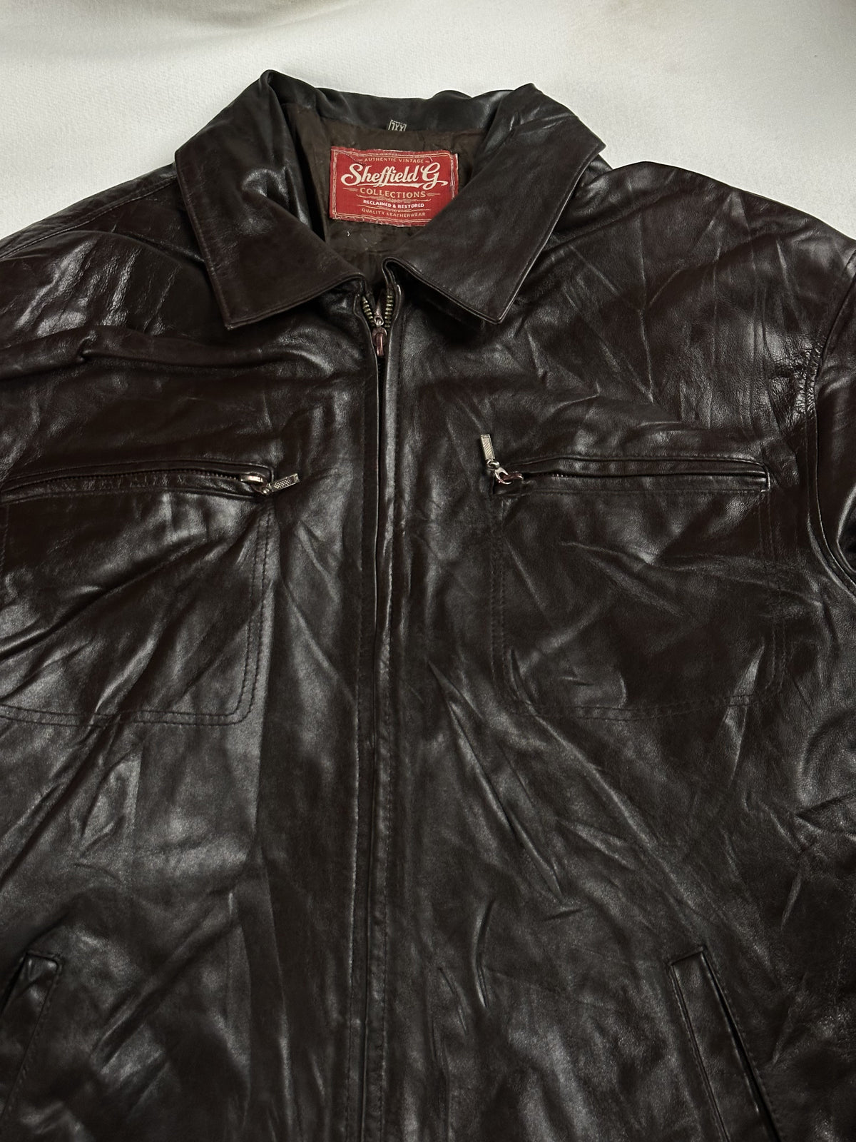 Close view of the shirt collar and the zipped chest pockets on the brown leather