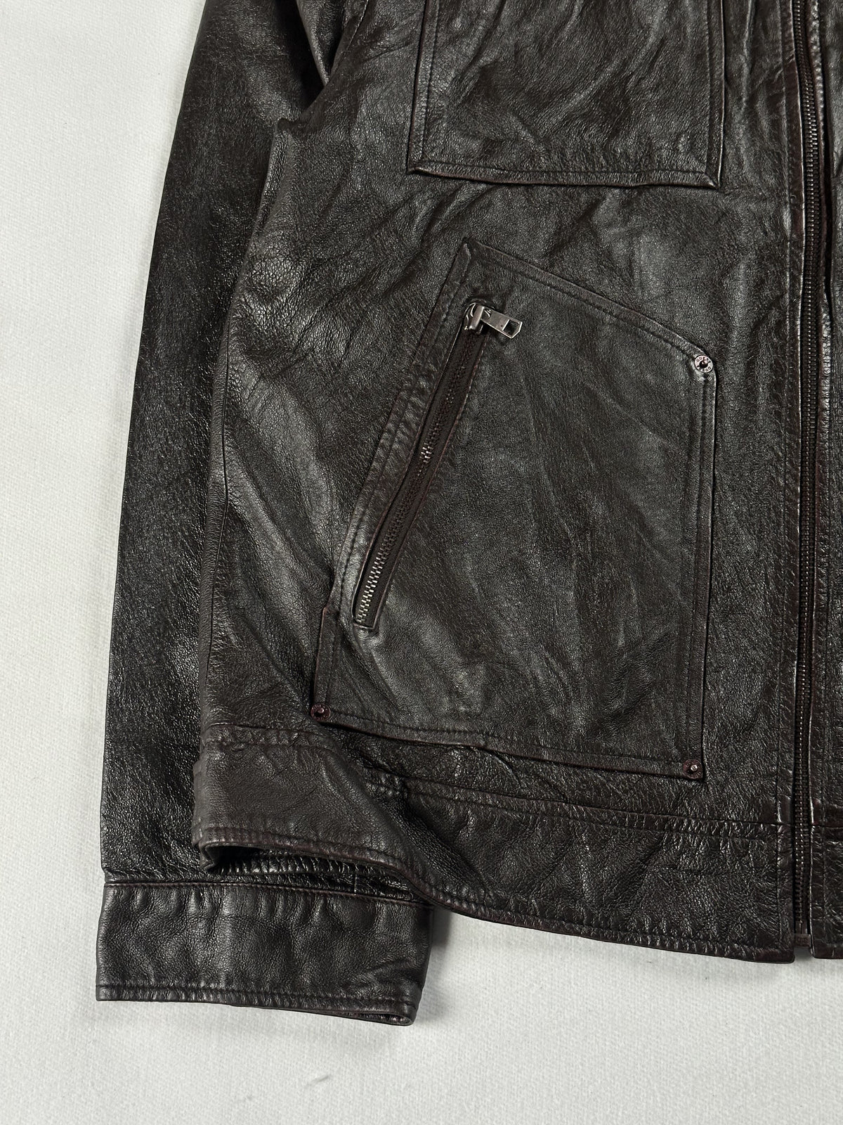 Buckle cuff and angled zip hand pocket at the lower left front of the brown leather