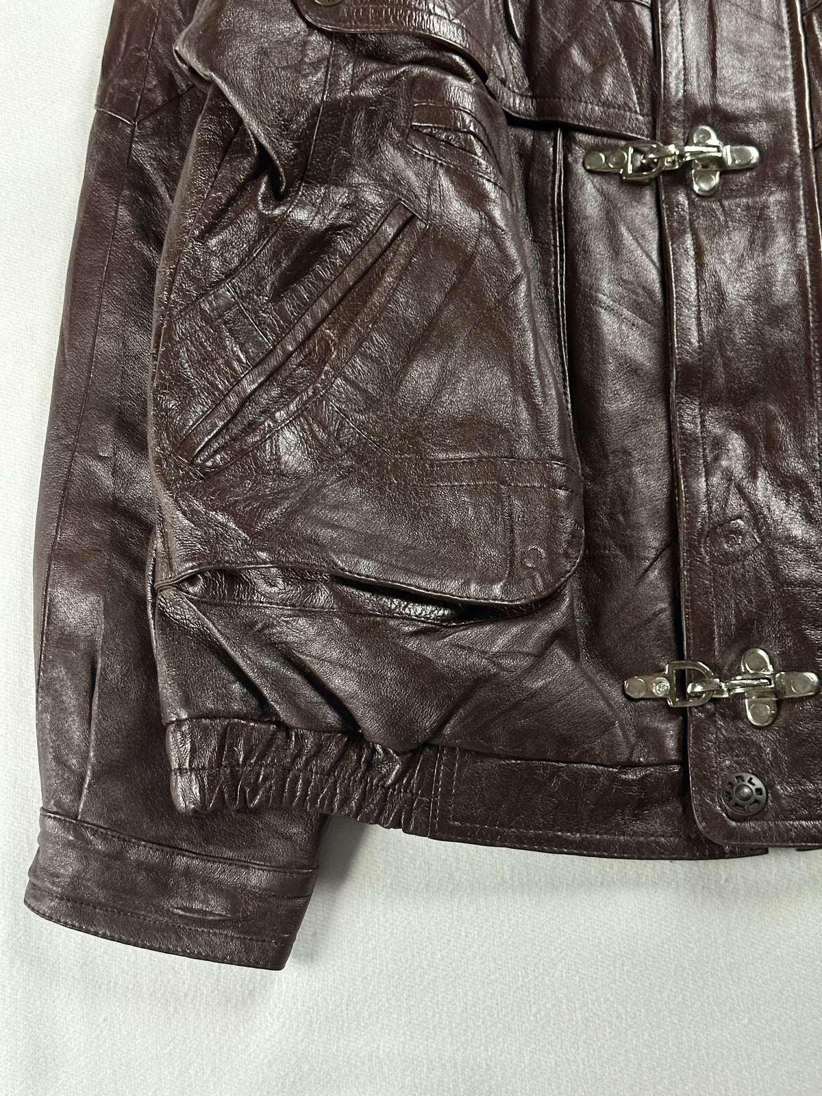 Embossed panel on the large flap pocket at the lower left, above the gathered waist