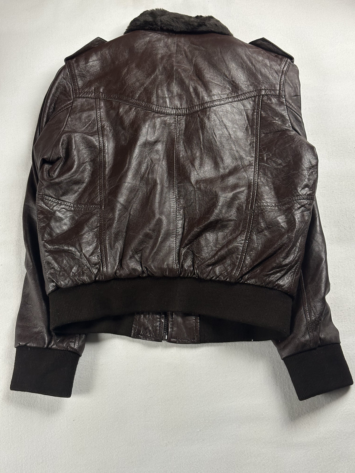 Back of the size M brown flight jacket showing the plain leather panel and knitted rib hem