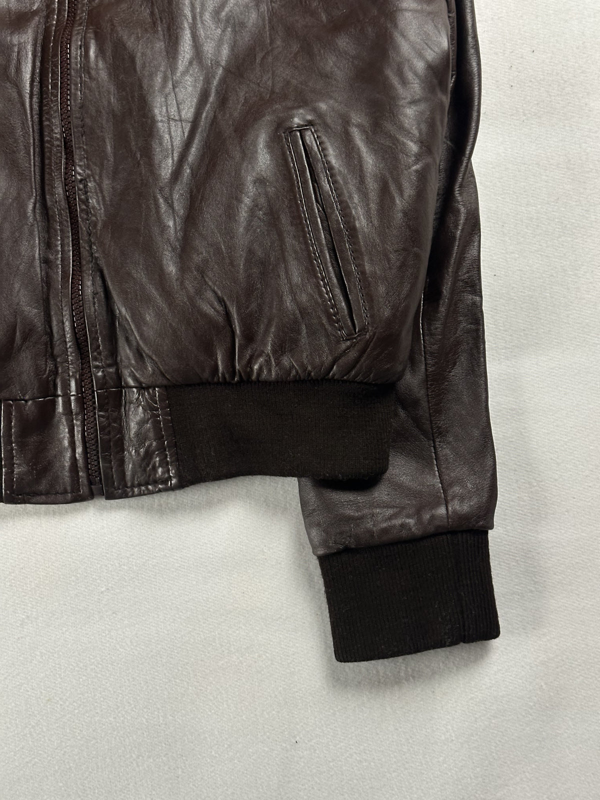 Right side welt pocket set into the brown leather, with the rib cuff resting on the hem