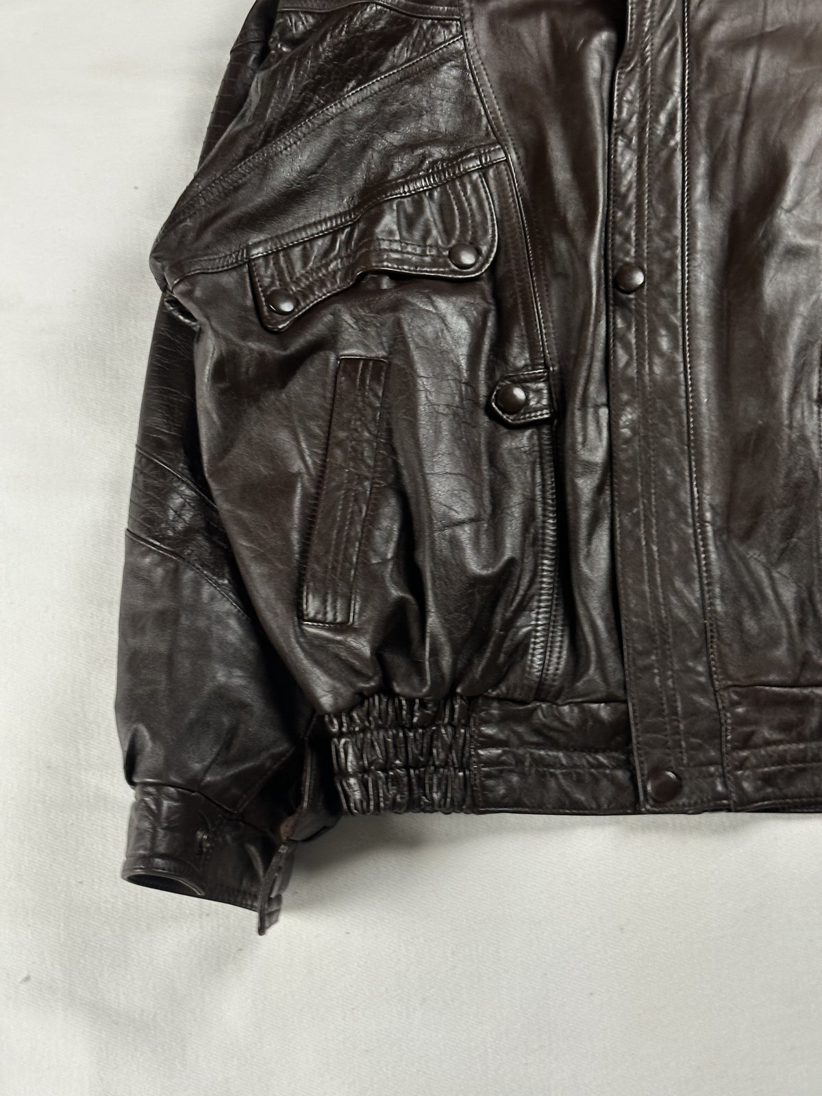 Lower left front detail showing a snap flap pocket, welt hand pocket and gathered waist