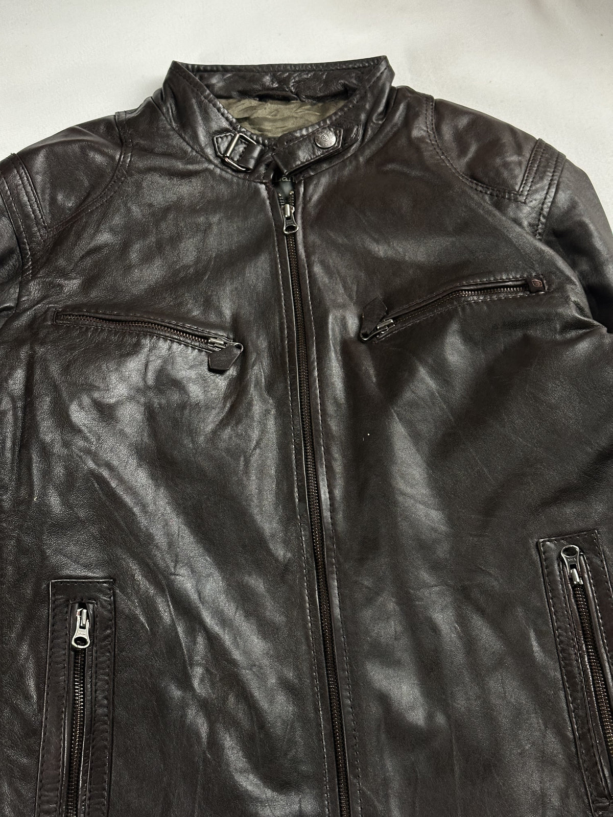 Buckled band collar and the slim zipped chest pockets at the top of the jacket