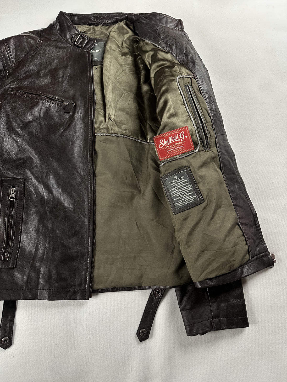 The jacket opened out to show its full olive lining and the strap at the cuff