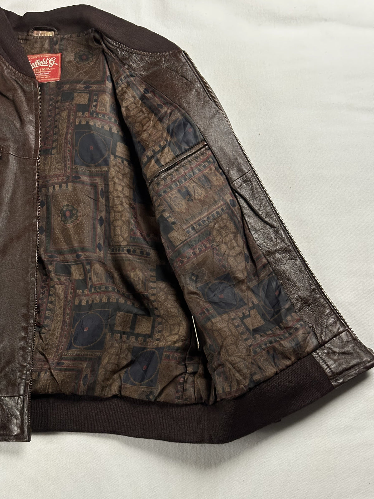 Patterned brown and grey lining held open inside the bomber, with an inner pocket