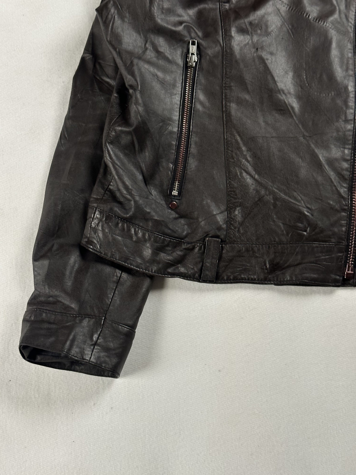 Detail of a plain cuff below the zipped hand pocket and the belted hem