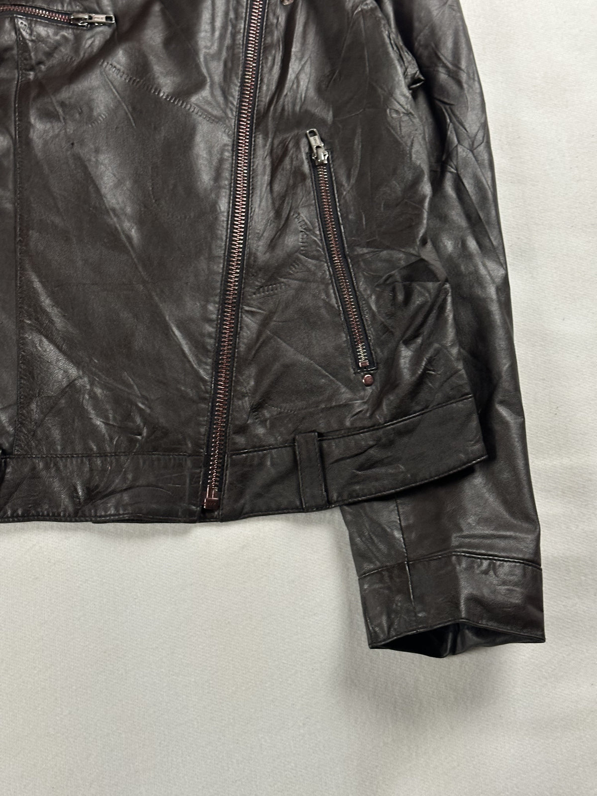 Angled view of the main zip, slanted zip pocket and belt fastening at the waist