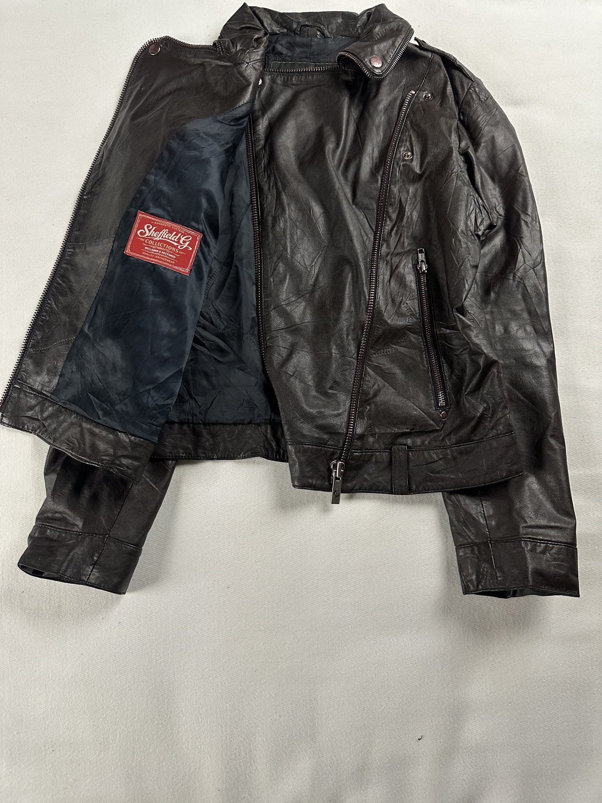 The biker jacket opened out to show the full navy lining beside the dark brown leather