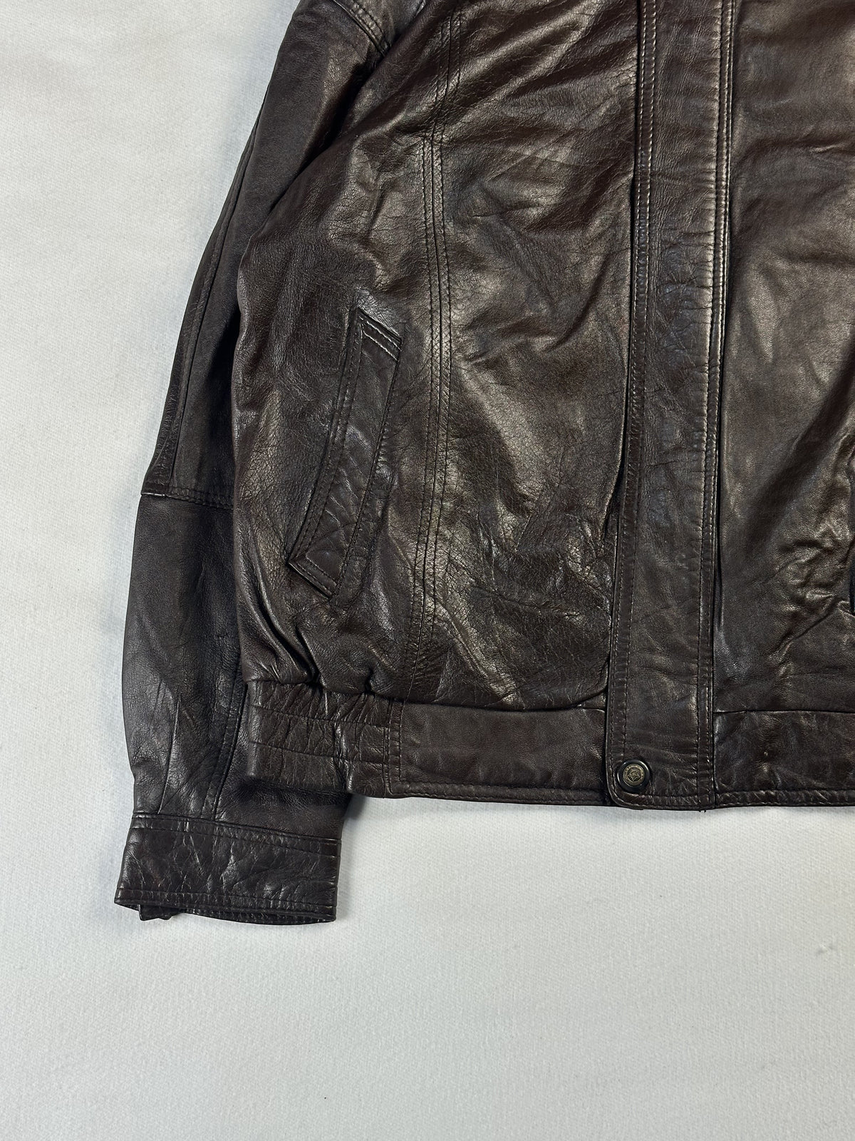Welt pocket, cuff and stretch waistband at the lower left of the brown leather