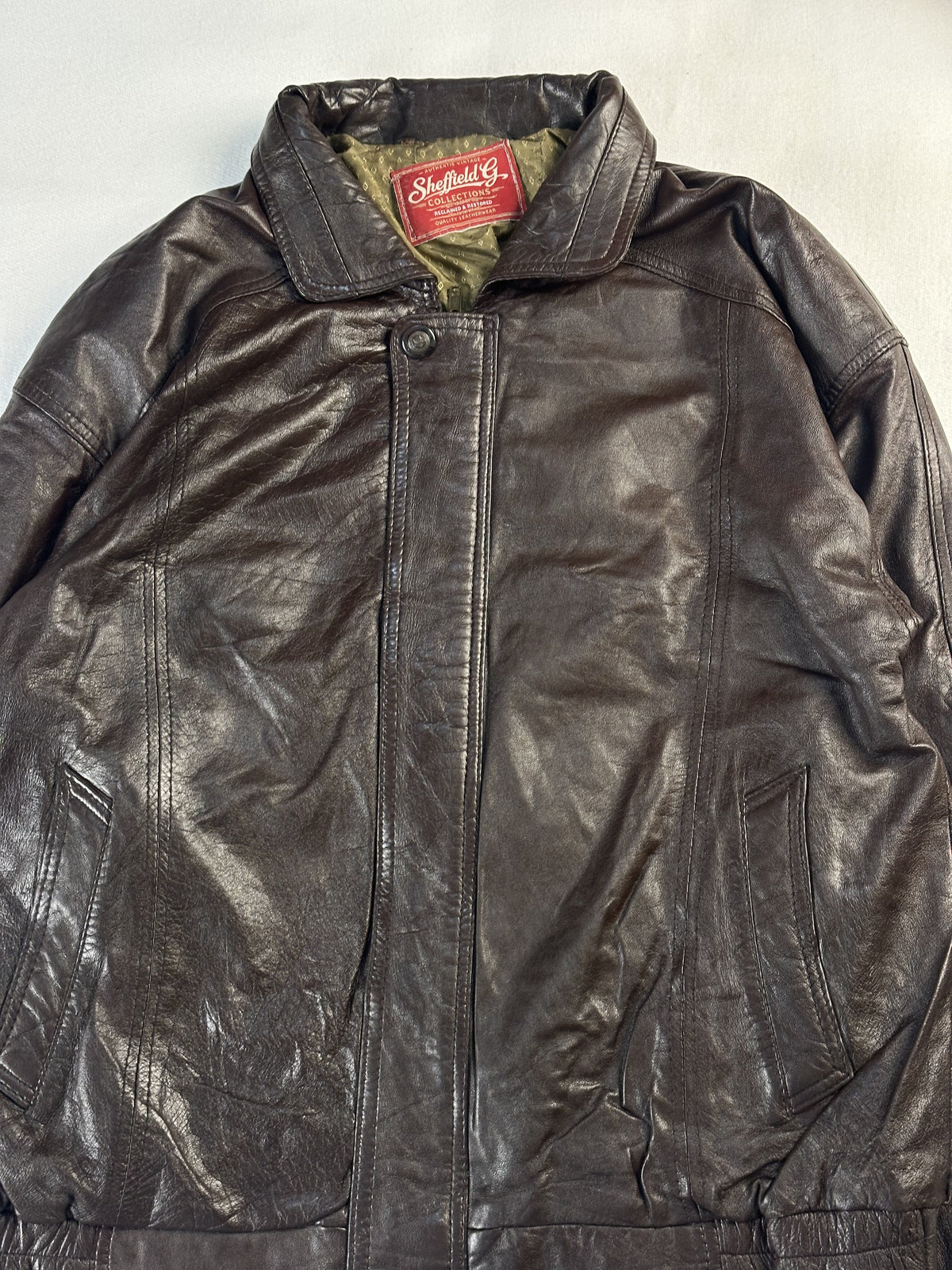 Close view of the collar and snap fastening with the olive lining just visible